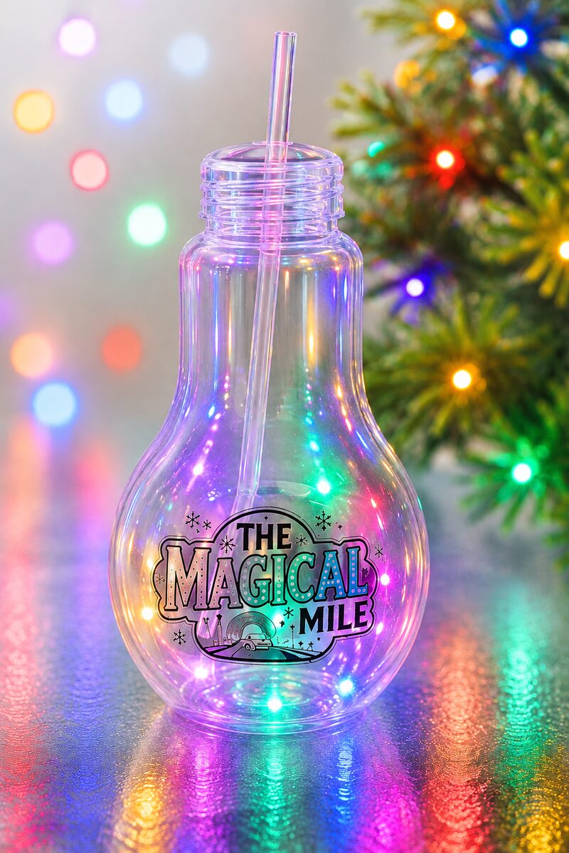 A clear light-bulb shaped souvenir cup with a straw, lit from inside in rainbow colours
